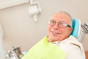 older man smiling sitting in dentist chair